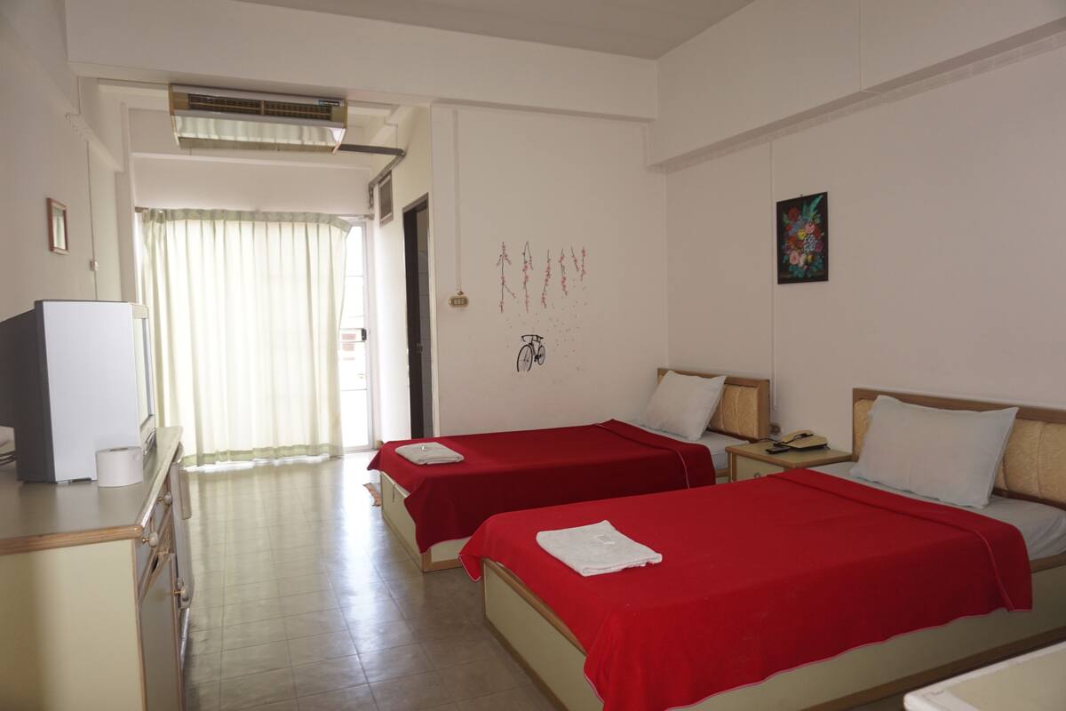 Habitación de hotel con dos camas, un escritorio, televisor y baño.