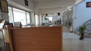 A reception area with a wooden reception desk, a glass display case, and a staircase leading to an upper floor.