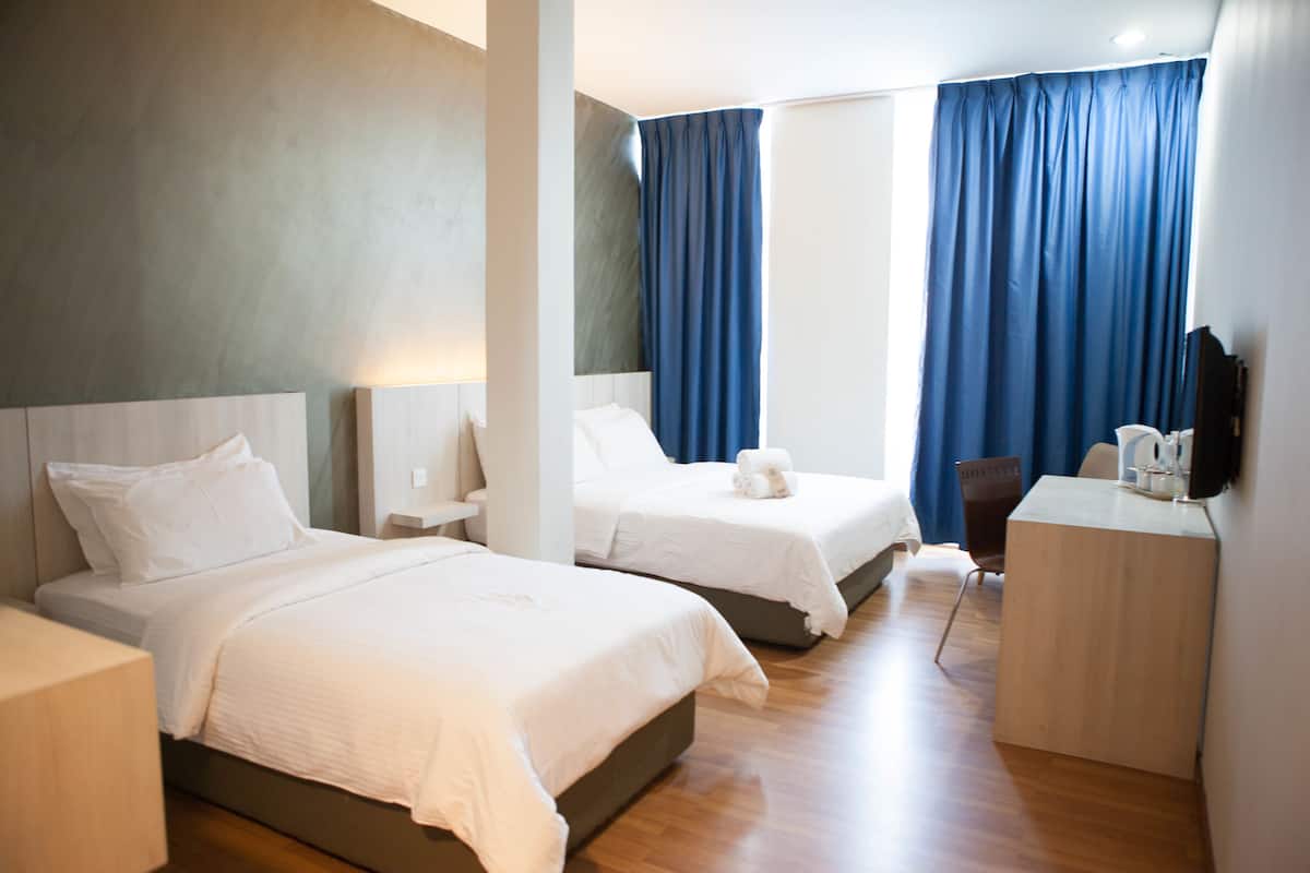Una habitación de hotel con dos camas, un escritorio, una silla y un televisor.