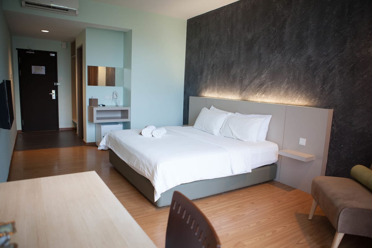 Una habitación de hotel moderna con una cama, mesita de noche y televisor.