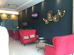 A modern living room with a red sofa, a round coffee table, and a TV mounted on the wall. - Inn86 (Bintulu)