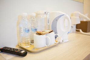 A hotel room with a coffee maker, two water bottles, a remote control, and a telephone on a tray. - Inn86 (Bintulu)
