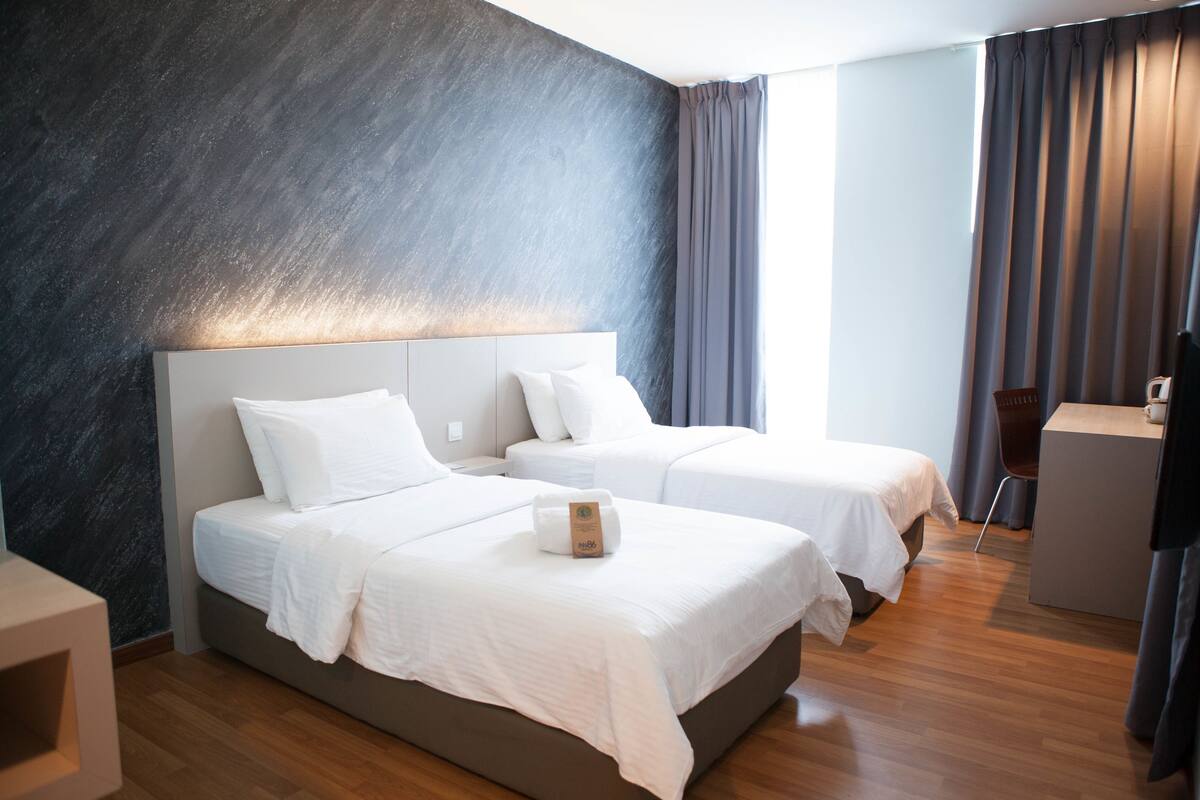 Una habitación de hotel moderna con dos camas, un escritorio y una silla.