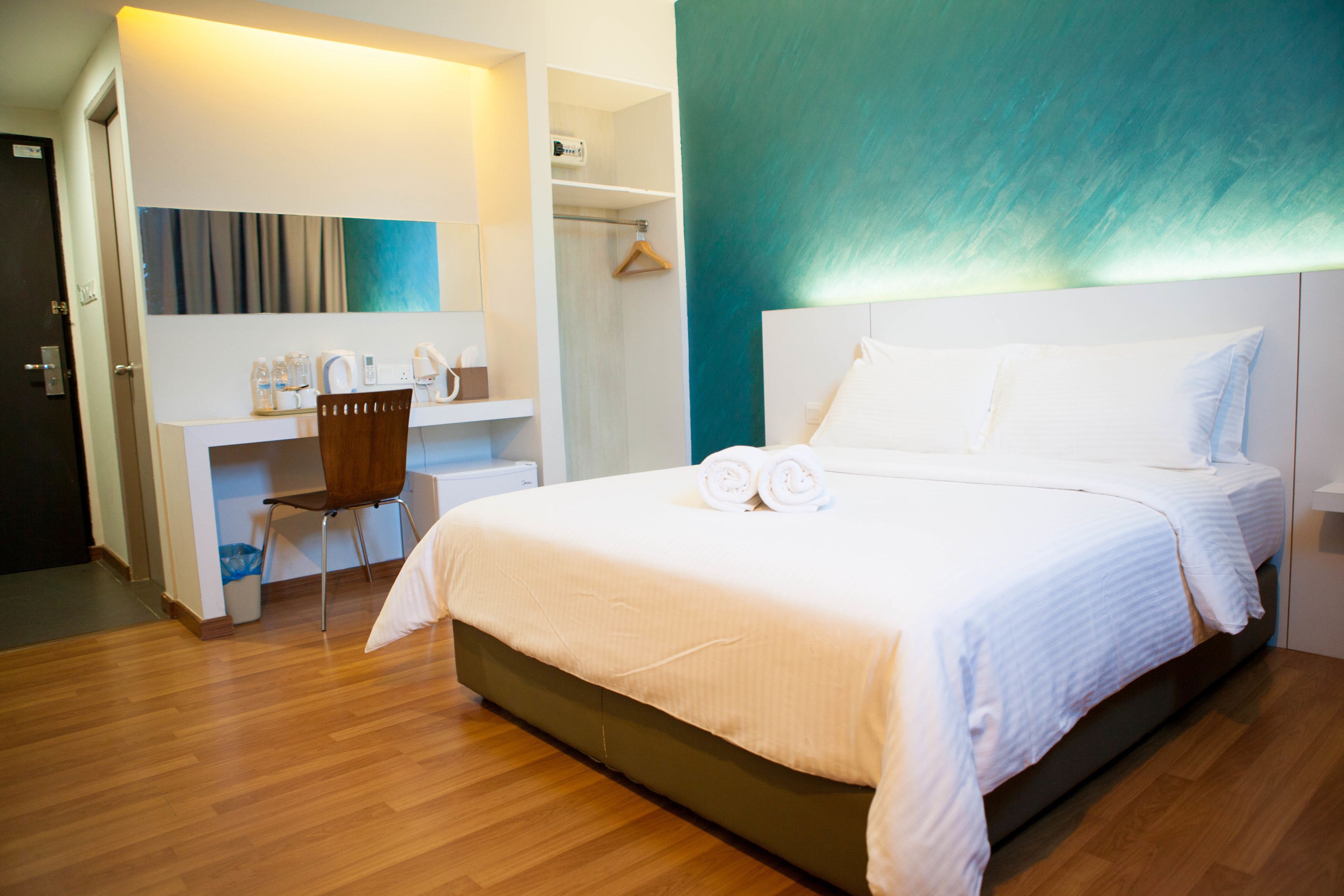 Una habitación de hotel moderna con una cama bien hecha, un escritorio con silla y un vestidor.