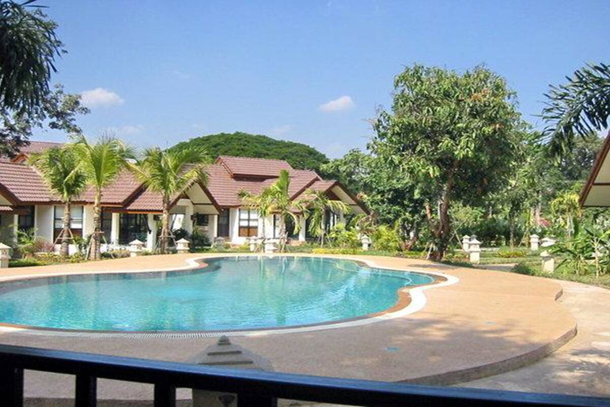 A resort with a large swimming pool, multiple villas with red roofs, and lush greenery.