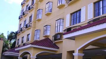 Un hôtel à plusieurs étages, avec une façade jaune, des balcons et une enseigne à l’entrée.