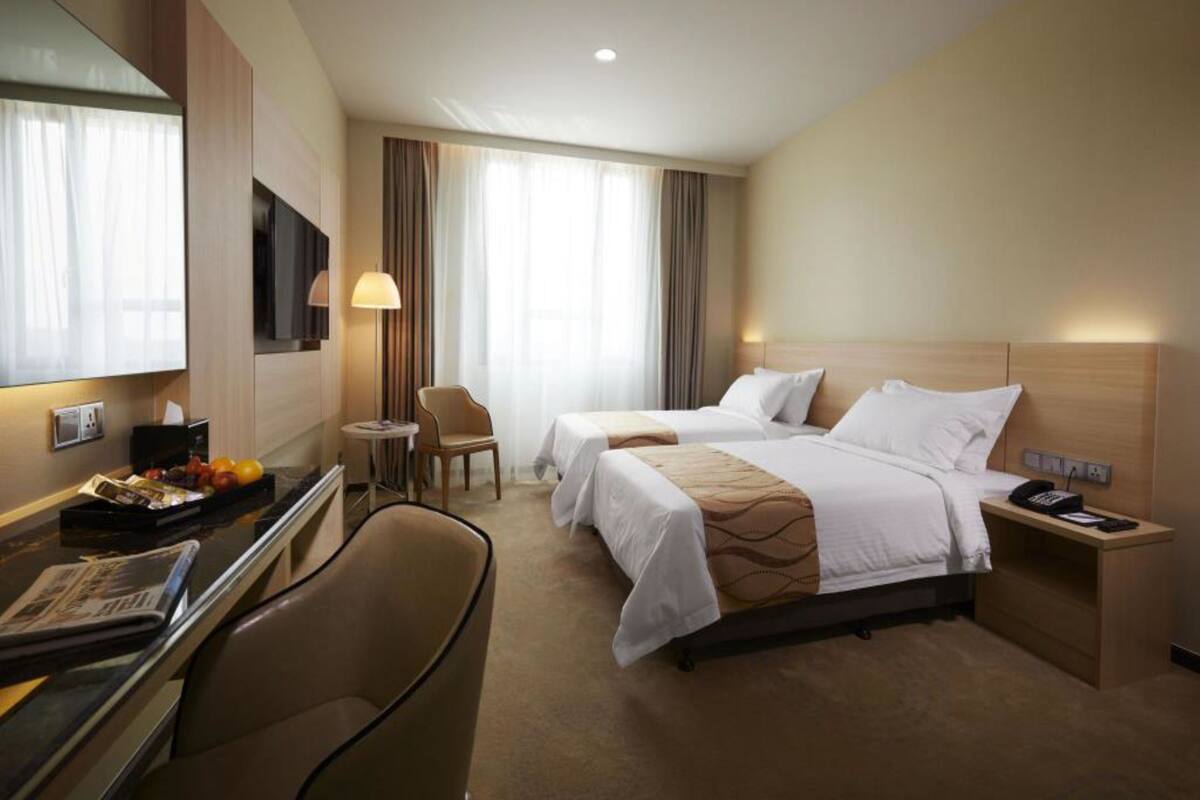 Habitación de hotel con dos camas, un escritorio, una silla, un televisor y una lámpara.