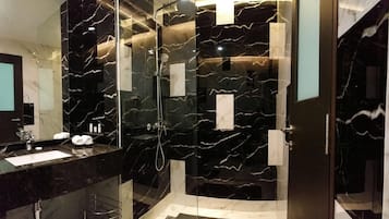 A modern bathroom with a glass shower enclosure, a marble vanity, and a large mirror.
