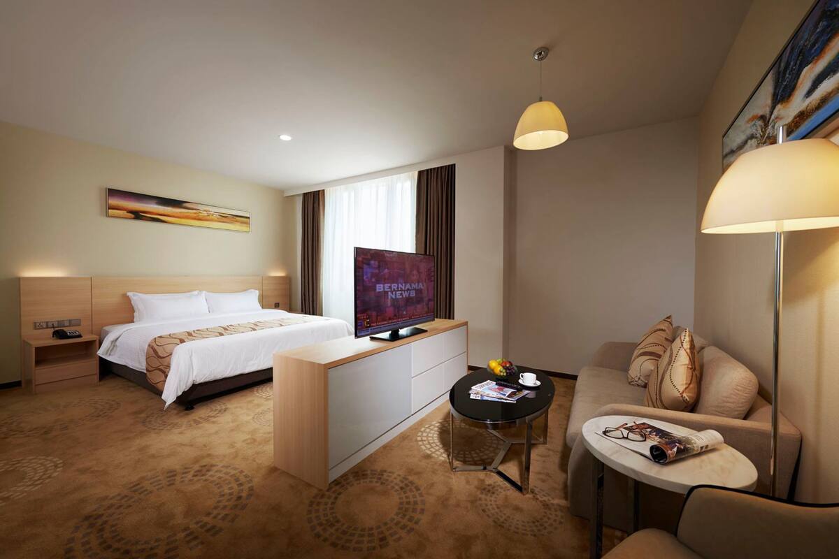 Habitación de hotel con cama, televisión, escritorio, sofá y lámpara.