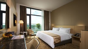 Habitación de hotel con una cama grande, un escritorio con lámpara, una silla y vistas al exterior.