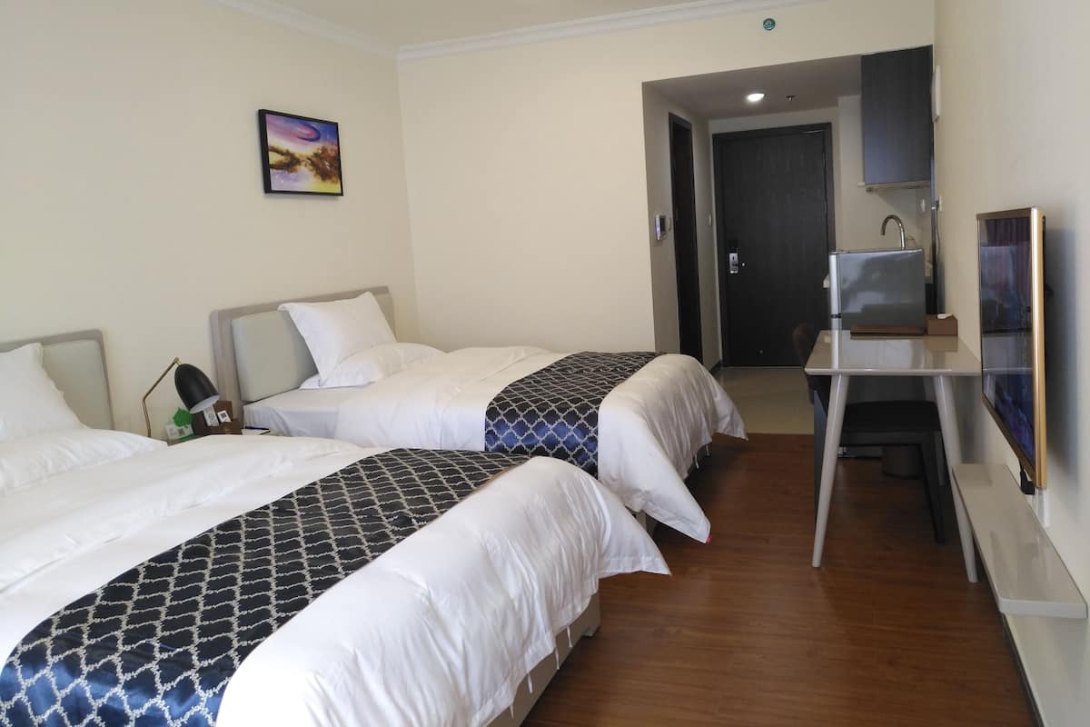Une chambre d’hôtel avec deux lits, un bureau, une télévision et une porte donnant sur une salle de bain.