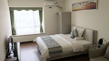 A hotel room with a bed, a desk, a chair, a wardrobe, and a painting on the wall.