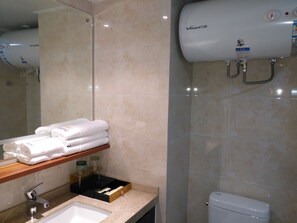Een badkamer met een wastafel, spiegel, handdoekhouder en een boiler.