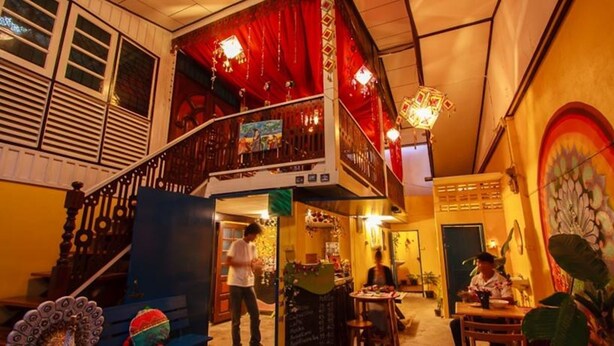 A multi-level interior with a staircase, a dining area, and a mural on the wall. - Chezmoi Handicraft & HomeStay (Chiang Rai)