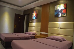 Habitación de hotel con dos camas, una puerta de madera y dos cuadros abstractos en la pared.