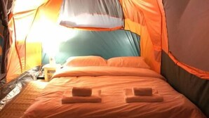Une pièce aménagée avec une tente, un lit, des oreillers et une table de chevet.