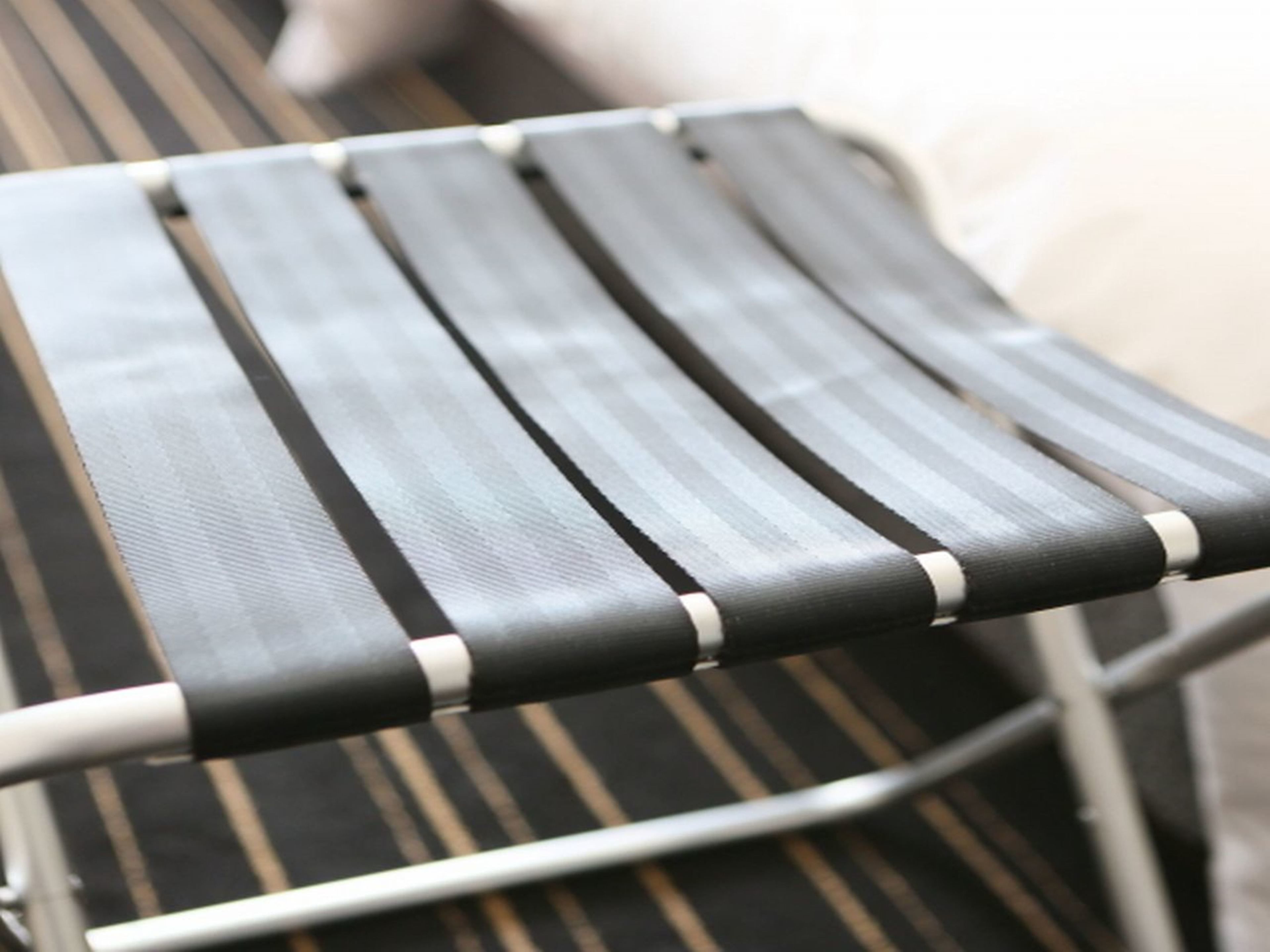 Primer plano de una silla a rayas con estructura metálica y asiento negro.