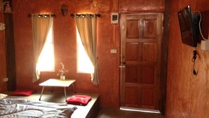 A room with a bed, a small table with a plant, and a wooden door. - Milin Guesthouse (Chiang Rai)