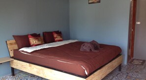 A bedroom with a wooden bed frame, a red bedspread, and multiple pillows. - Milin Guesthouse (Chiang Rai)