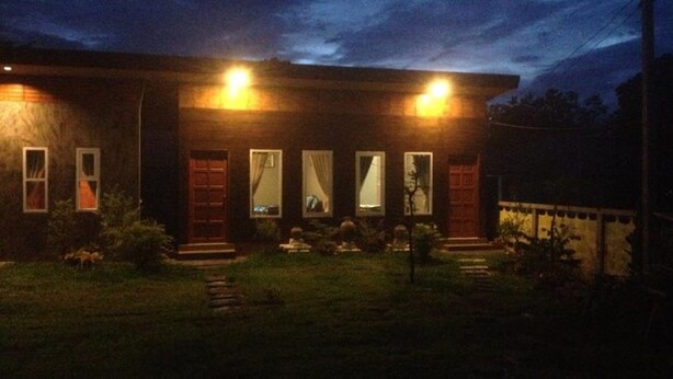 A two-story house with a front porch, a small garden, and a well-lit exterior at night. - Milin Guesthouse (Chiang Rai)