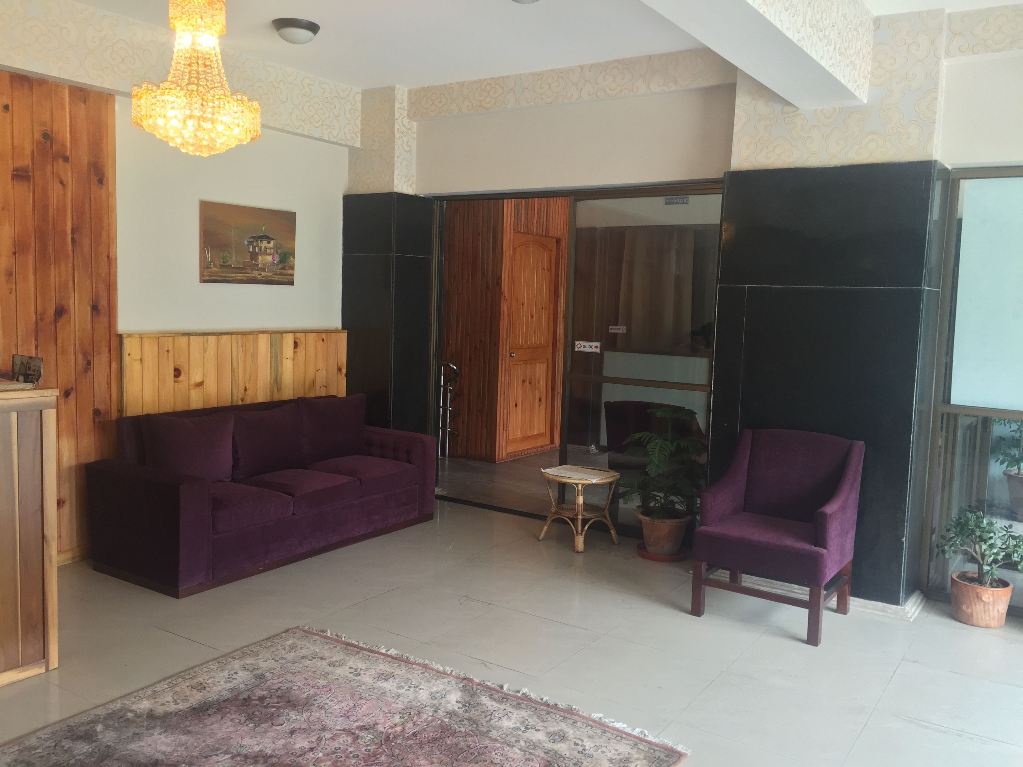 Una sala de estar con un sofá morado, un aparador de madera, una mesita y una silla.