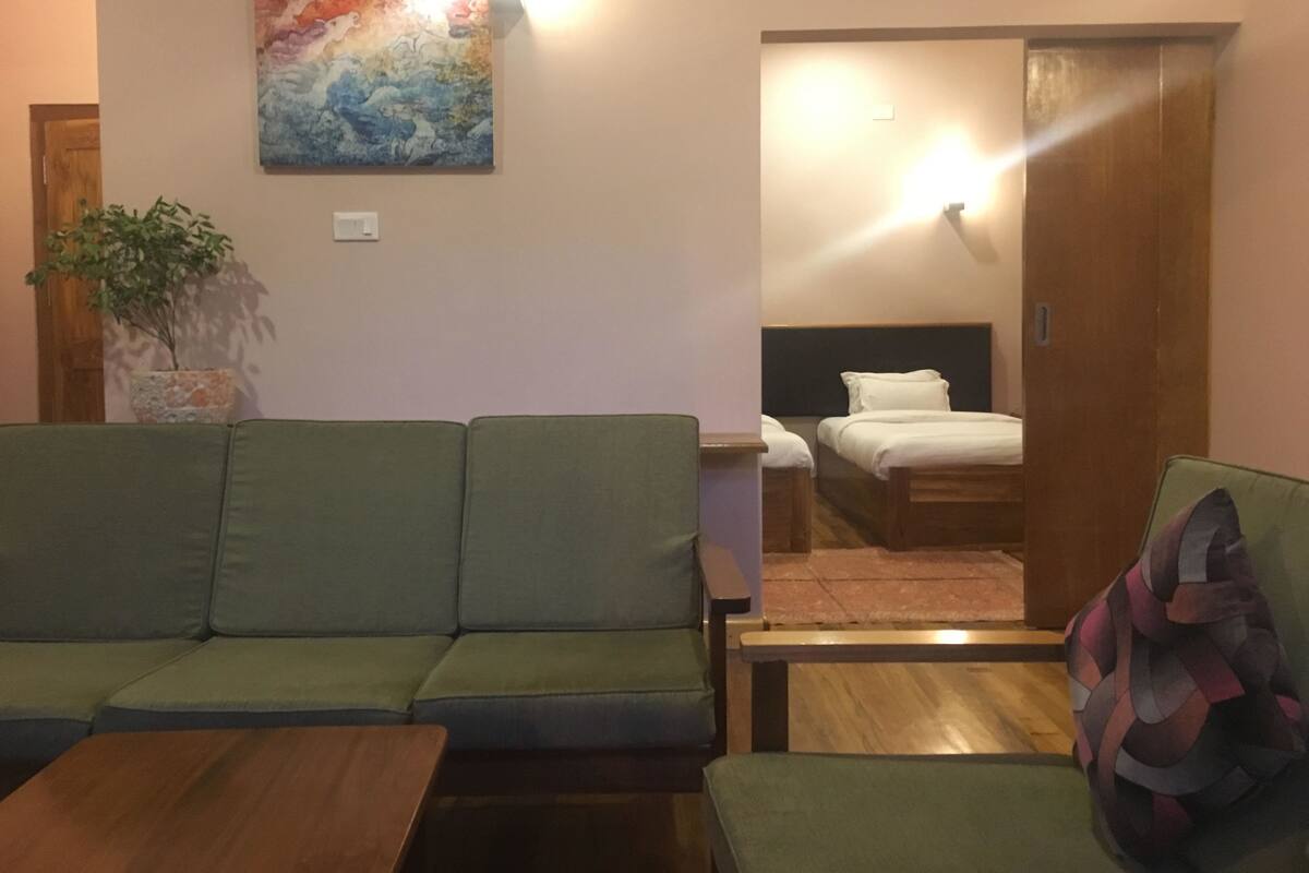 A living room with a green sofa, a wooden coffee table, and a colorful abstract painting on the wall.