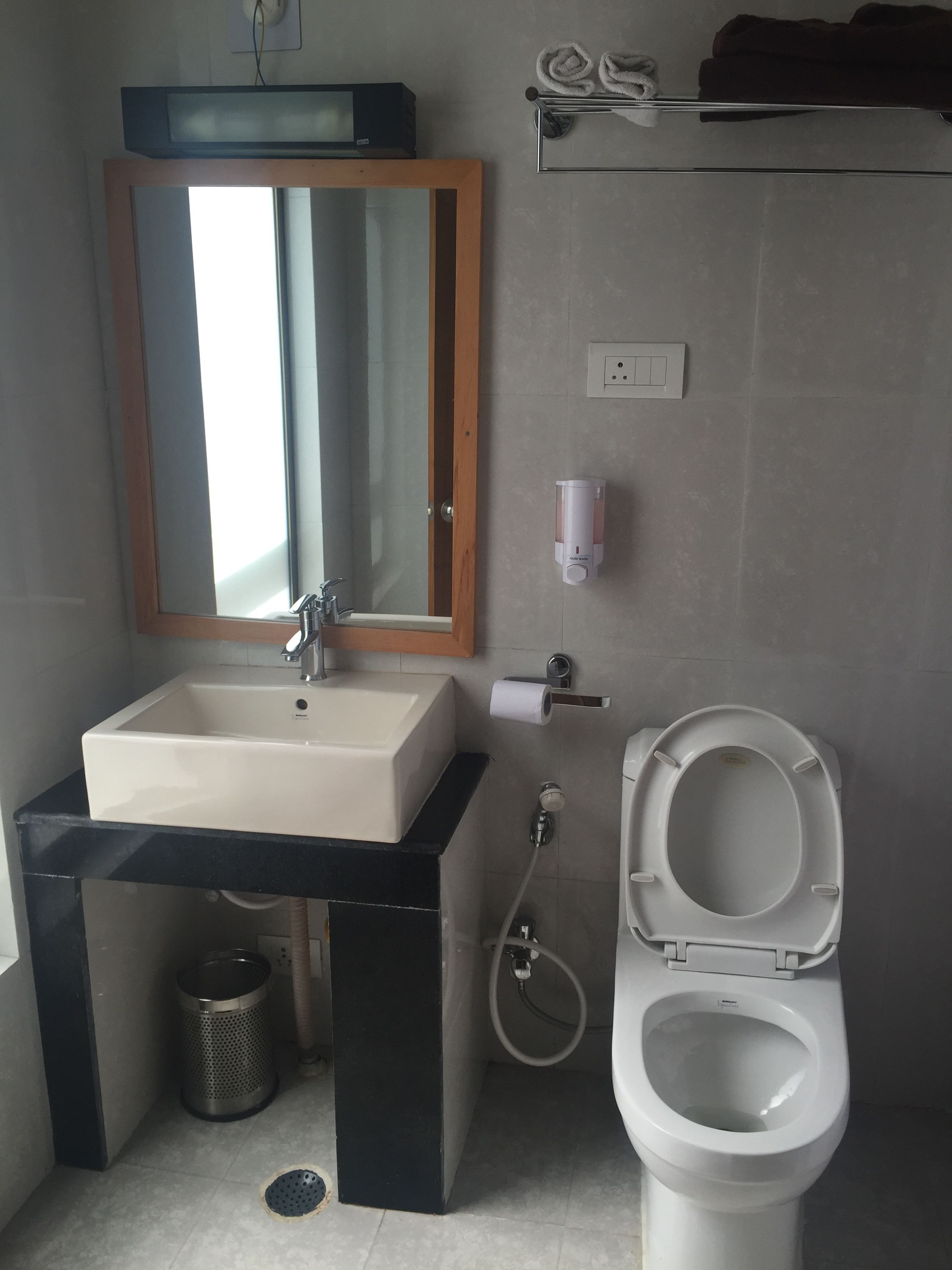 Een badkamer met een wastafel, spiegel, toilet en handdoekhouder.