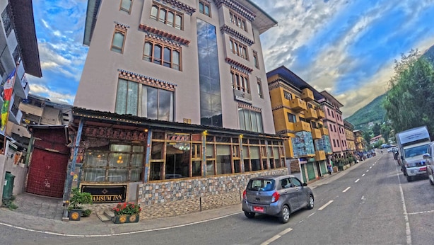 En byggnad med flera våningar, en fasad av sten, en skylt med texten ”Krasnaya Bank” och en parkerad bil på gatan.