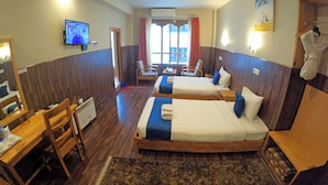 Ett hotellrum med två sängar, ett skrivbord, en stol, en TV och utsikt över omgivningarna.