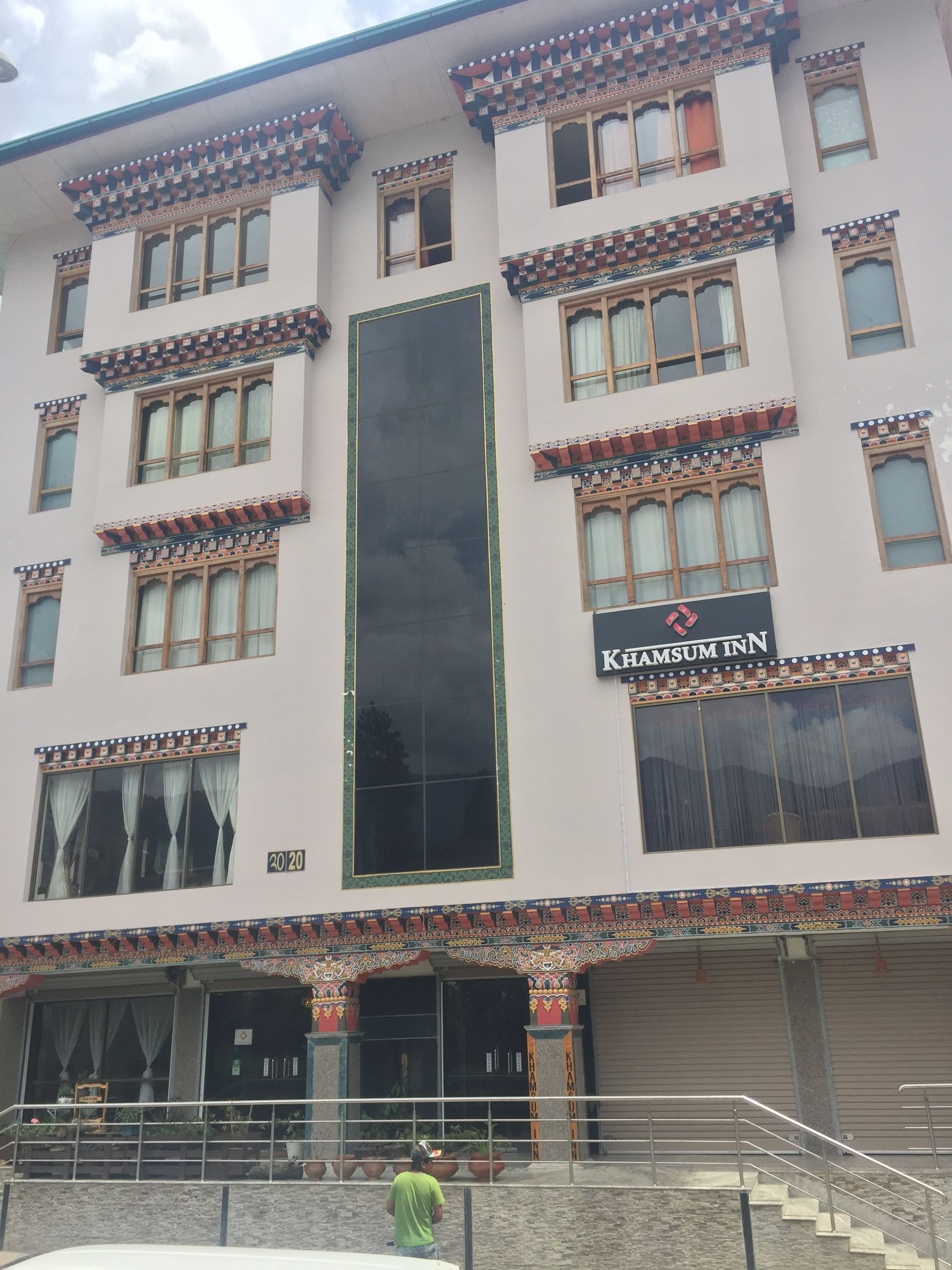 Um edifício com uma placa que diz "Khamsum Inn" e uma grande janela vertical.