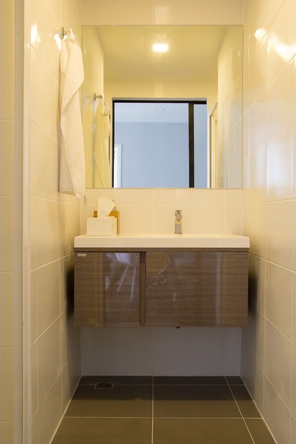 A modern bathroom with a white vanity, a mirror, and a towel hanging on the wall. - Establiss By Weena (Bangkok)