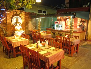 An outdoor restaurant with brick walls, wooden tables and chairs, and string lights.