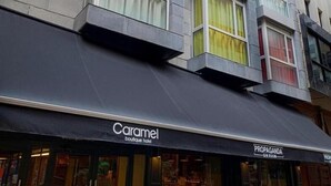 Un hotel boutique Caramel con toldo negro, zona de estar exterior y una sala de ginebra Propaganda.