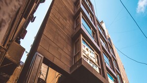 Un edificio con un hotel boutique llamado 'Caramel' en la planta baja, con un diseño arquitectónico moderno, ventanas amplias y un área de estar al aire libre.
