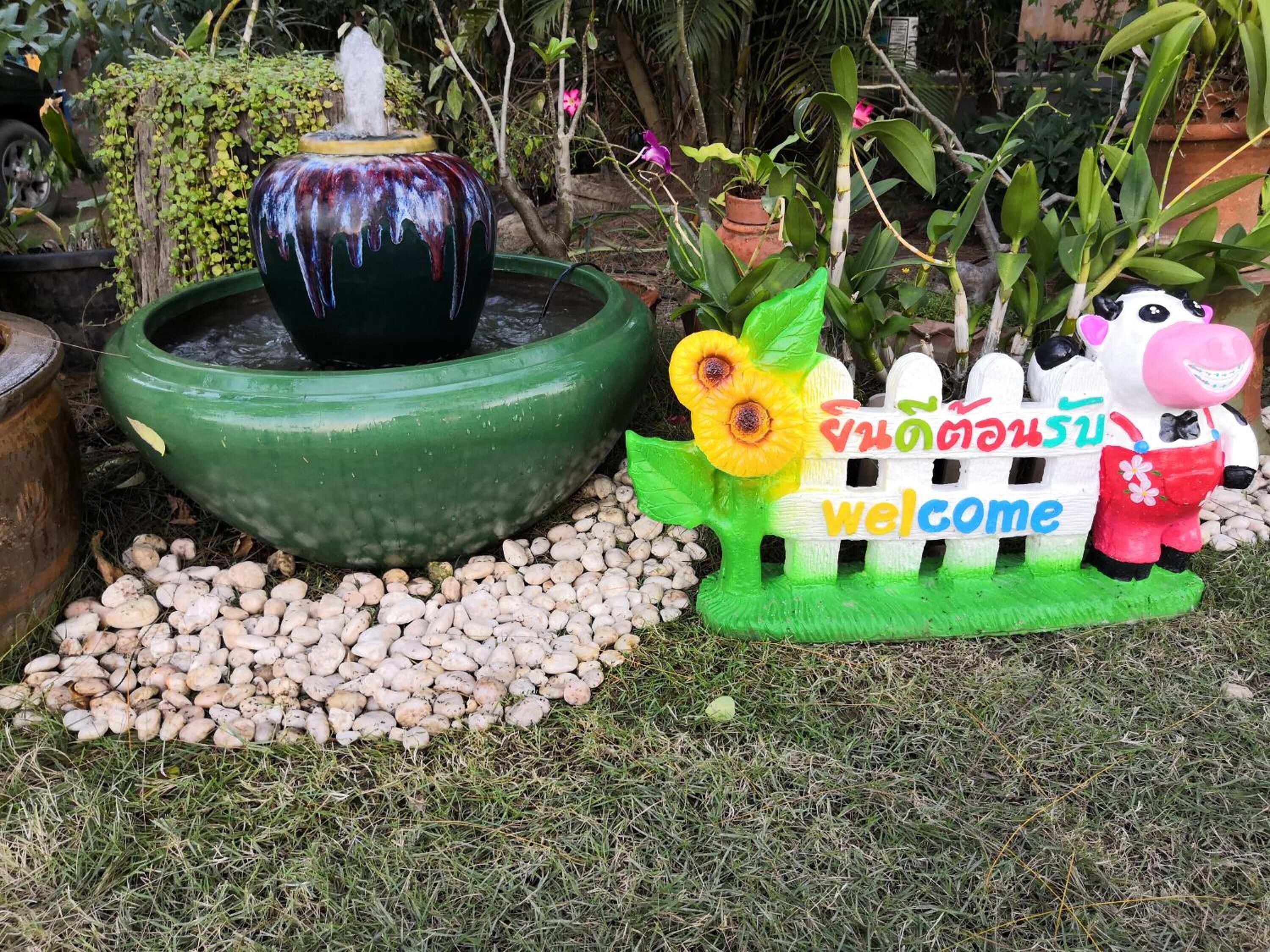 Un jardin agrémenté d’une fontaine, d’un panneau d’accueil et d’une clôture décorative.