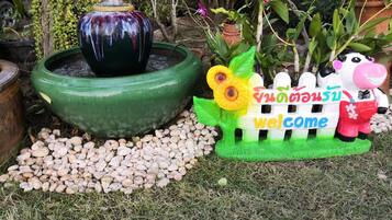 Un jardin agrémenté d’une fontaine, d’un panneau d’accueil et d’une clôture décorative.