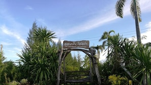 A wooden sign with contact information in a tropical setting.