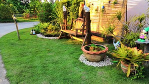A well-maintained garden with a wooden bench, a decorative planter, and various potted plants.