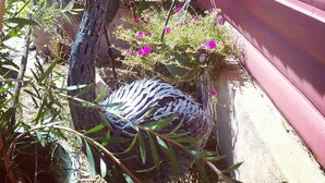En fågelskulptur i en trädgårdsmiljö, med ett staket och blommande växter.