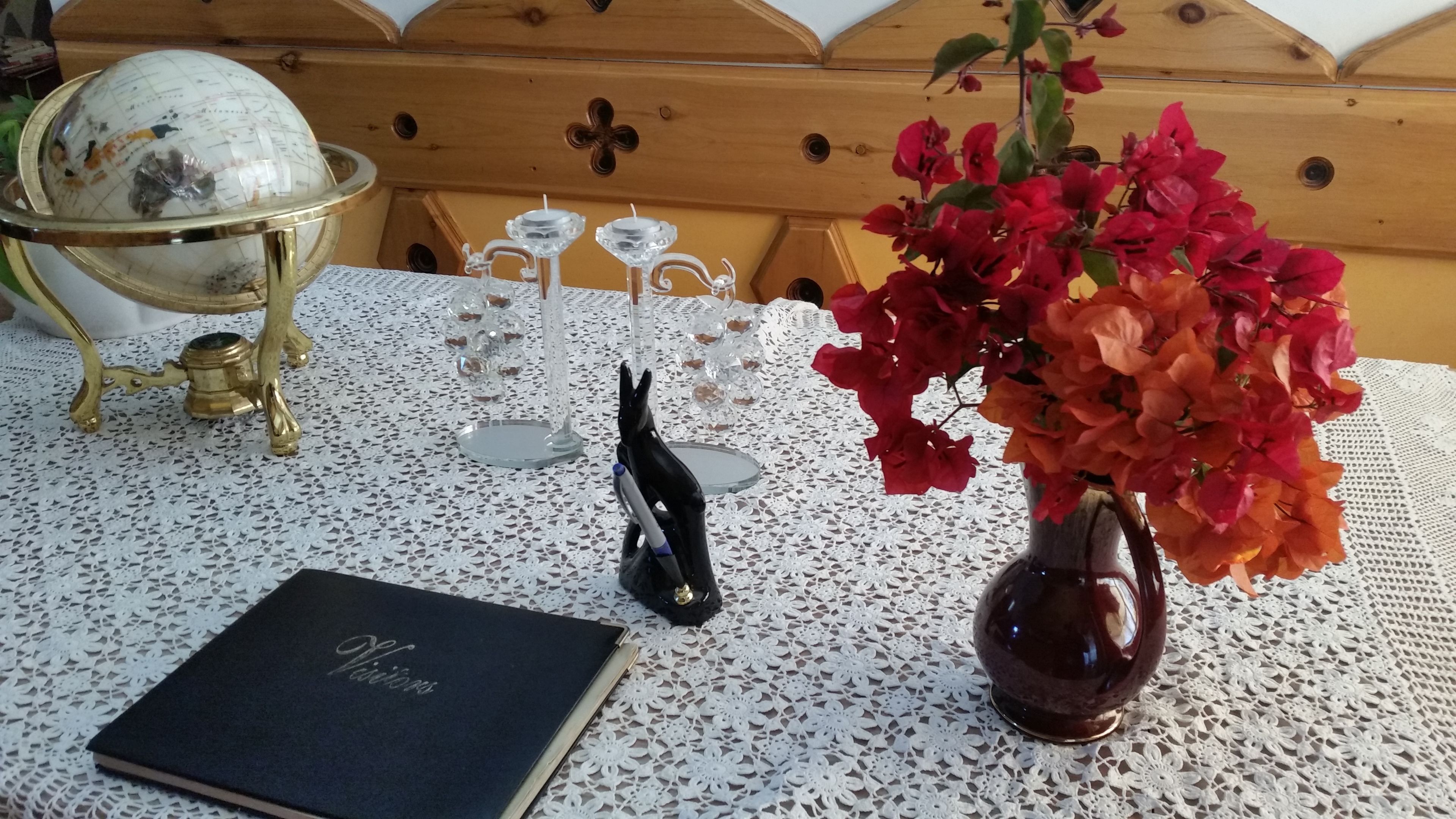 A table with a globe, a book, a vase with flowers, and a decorative stand.