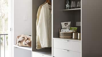 A modern room with a grey wardrobe, a wicker chair, and a small dining table.