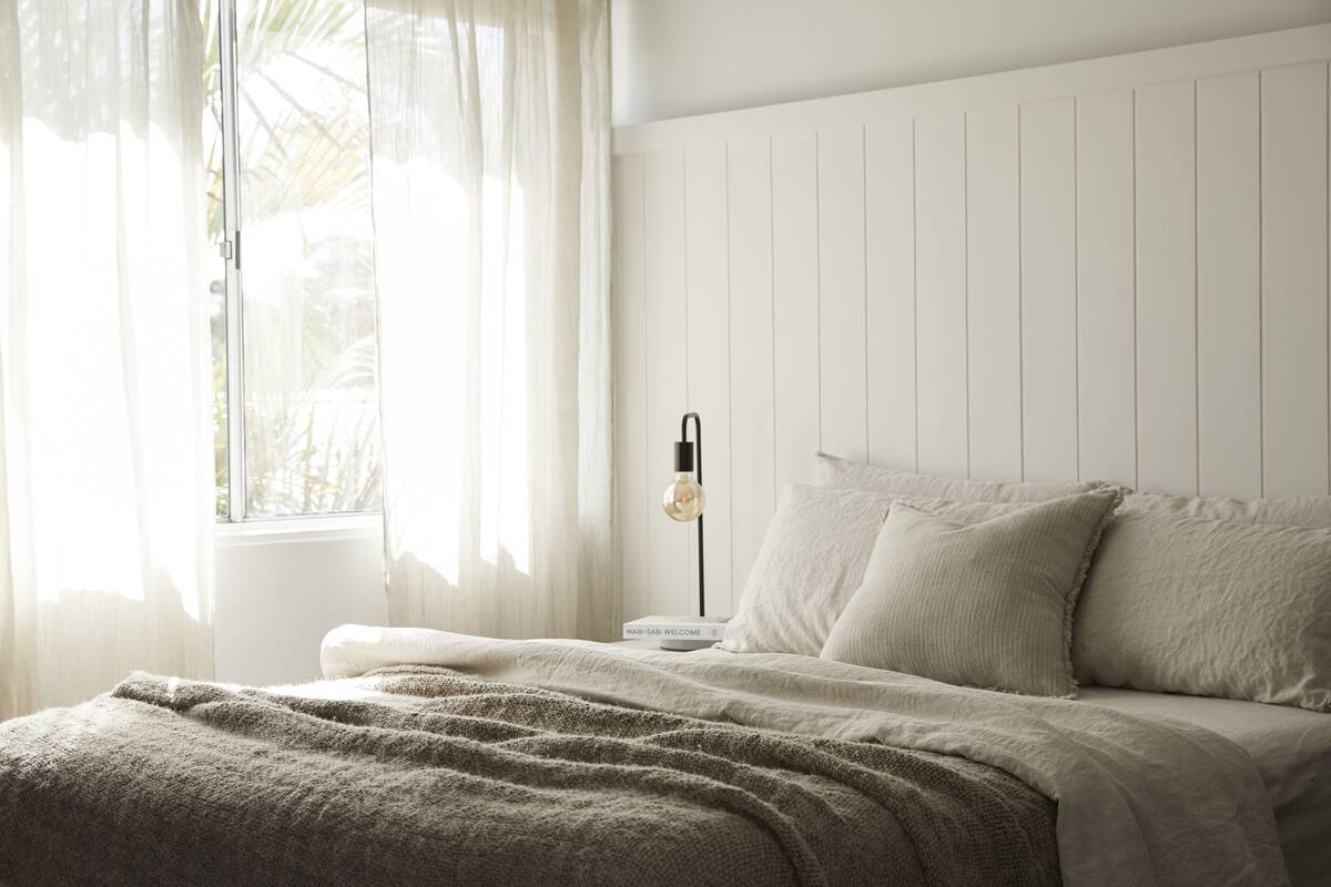 A bedroom with a bed, a bedside table, and a lamp.