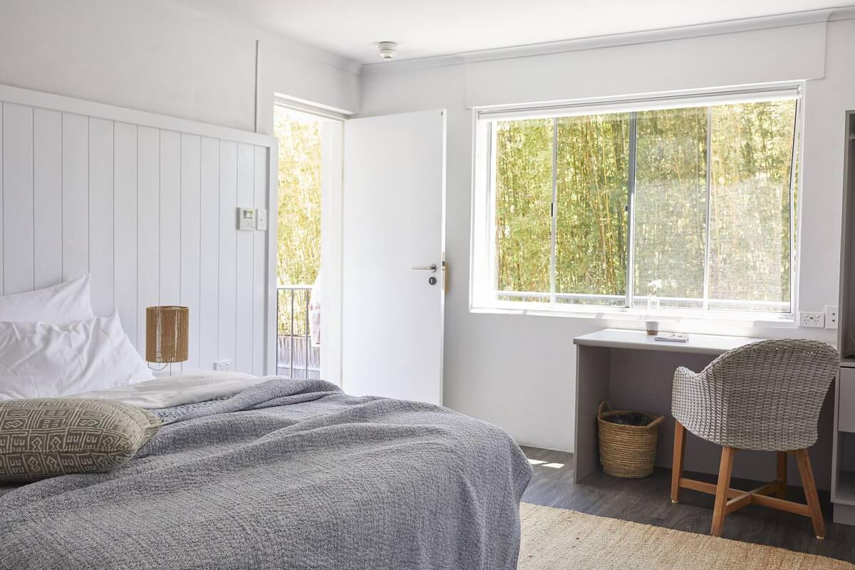 A bedroom with a bed, a desk, and a chair.