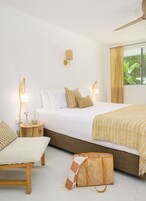 A neatly arranged bedroom with a bed, bedside tables, a lamp, and a window with curtains.