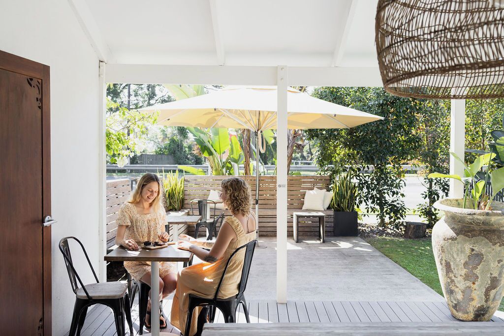 Une terrasse extérieure avec deux tables, des chaises et un grand parasol.
