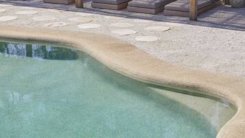 A swimming pool with a wooden deck and lounge chairs.