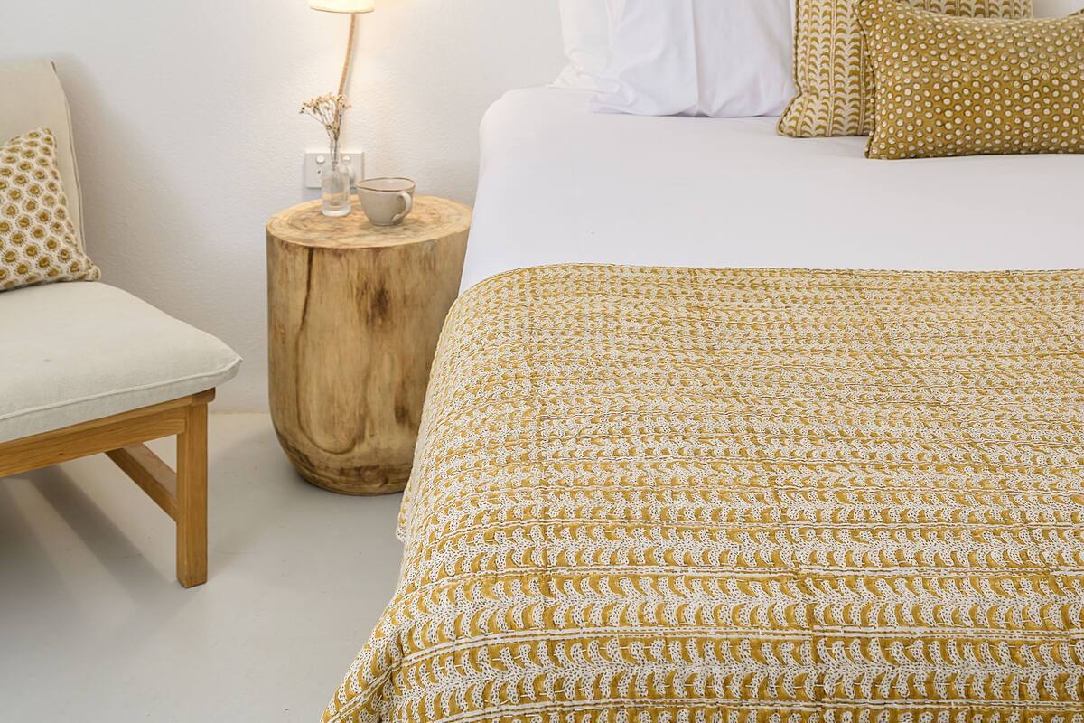 A bedroom with a bed, bedside table, lamp, and a wall-mounted light fixture.
