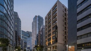 A cityscape with modern high-rise buildings, a prominent hotel sign, and a street with street lamps. - Nesthotel alt. Meguro Station (Tokyo)