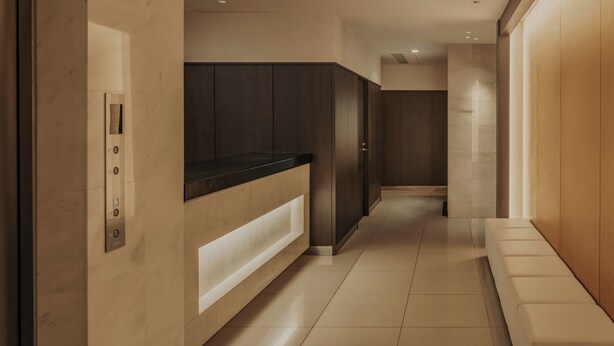 A hallway with a modern elevator, a bench, and a wall with a label. - Nesthotel alt. Meguro Station (Tokyo)