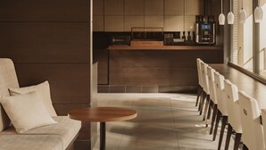 A modern interior with a sofa, a round table, a kitchen area, and a bar with seating. - Nesthotel alt. Meguro Station (Tokyo)